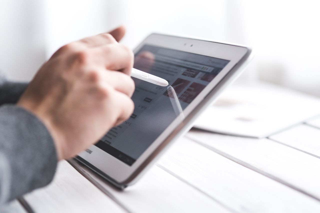 Close-up of a hand using a stylus on a tablet, showcasing digital technology interaction.